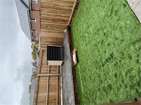 Green lawn beside timber decking and boundary fencing
