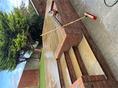 Raised paved patio with brick-edged steps and garden lawn