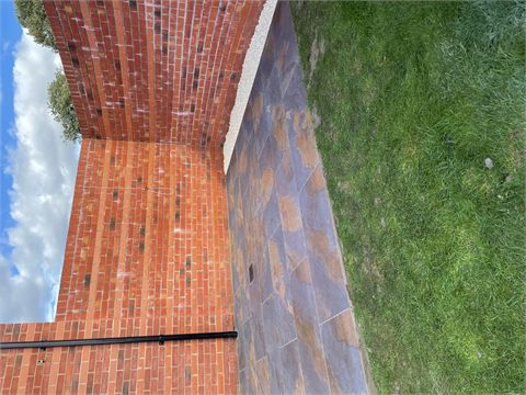 Multicoloured paving beside a lawn and brick boundary wall