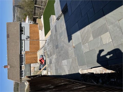 Rear garden with paving, green lawn and timber fencing