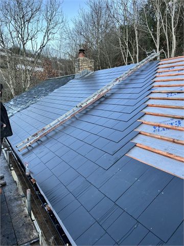 Roof covering being laid beside exposed battens and a roof ladder
