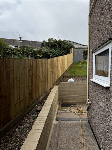 Timber boundary fencing beside a narrow path and raised garden bed
