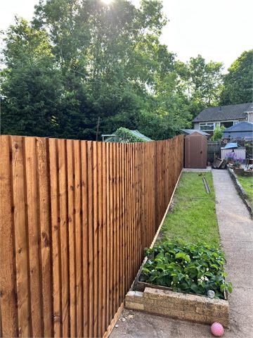 Timber fence running beside a garden lawn and raised bed