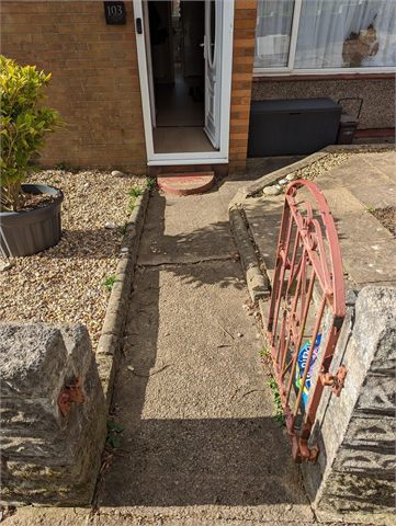 Exposed ground and entrance steps beside a red handrail