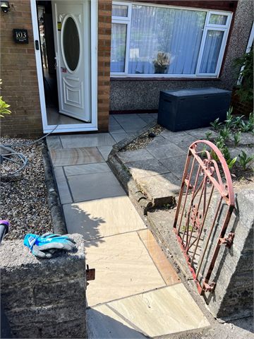 Paving and steps beside a house entrance and red handrail