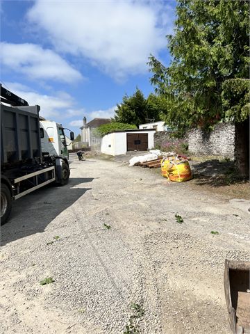 Driveway ground preparation beside a truck and garden wall