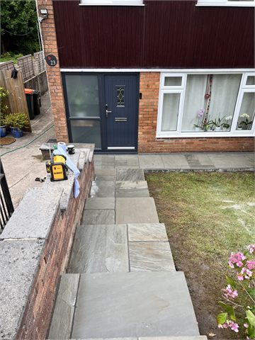 Paved front steps beside a low wall and garden lawn
