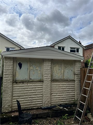 Garage roof and boarded frontage with a ladder at the side