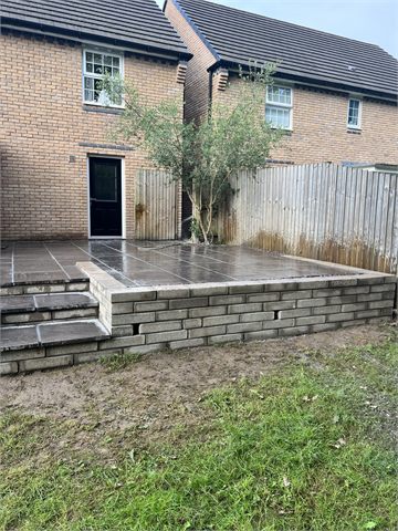 Raised paved patio and garden steps by rear house doors