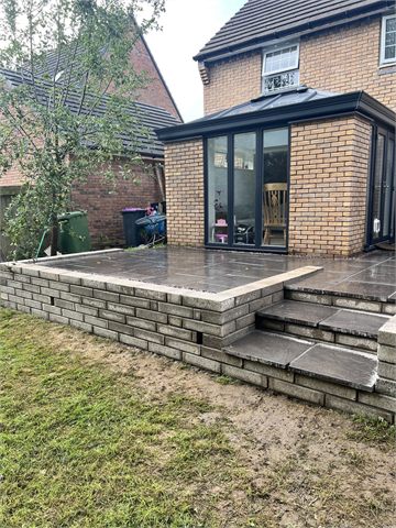 Paved patio and steps beside a glazed garden room