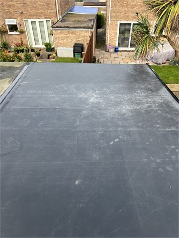 Flat dark roof surface overlooking a rear garden