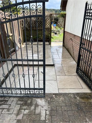 Paved entrance viewed through open metal gates