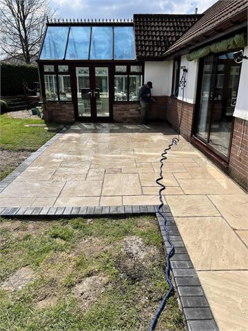 Paved patio adjoining a conservatory and lawn