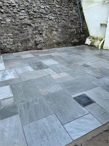 Multicoloured paving beside a stone garden wall