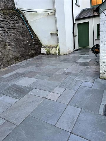 Courtyard paving beside stone and rendered house walls